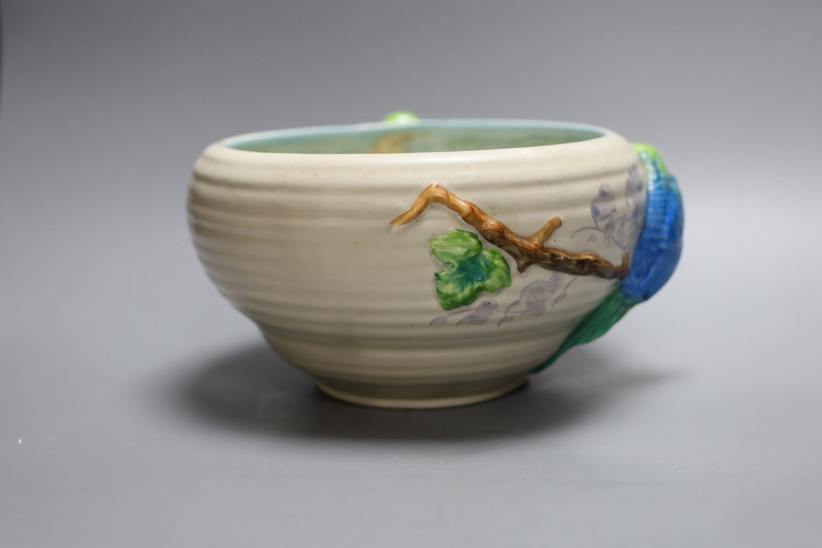 A late Clarice Cliff bowl with perched parrot decoration, 12cm tall